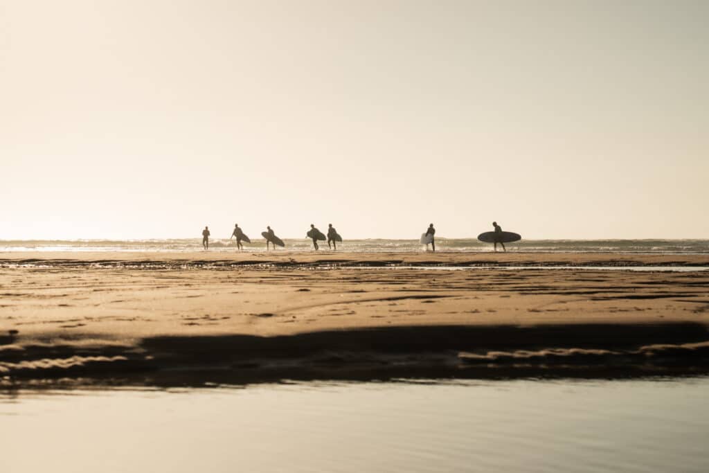 Landscape beach scene showing people running to the sea with surfboards and beautiful golden tones